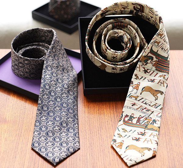 Selection of silk ties including Bayeux Tapestry-inspired and Pilgrim Badge designs displayed in gift boxes. - Ties Collection.