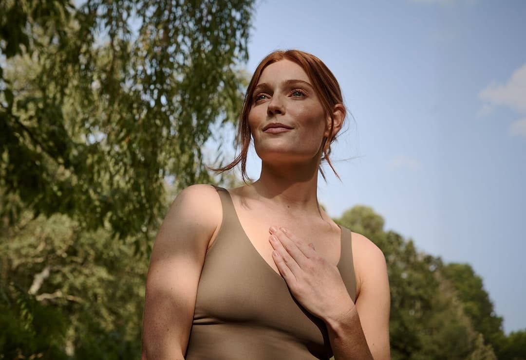 Woman with hand placed over her chest.