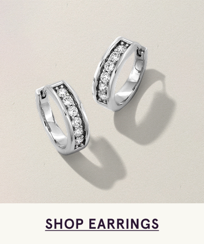 Pair of white metal huggies with central strip diamonds. Click here to shop earrings