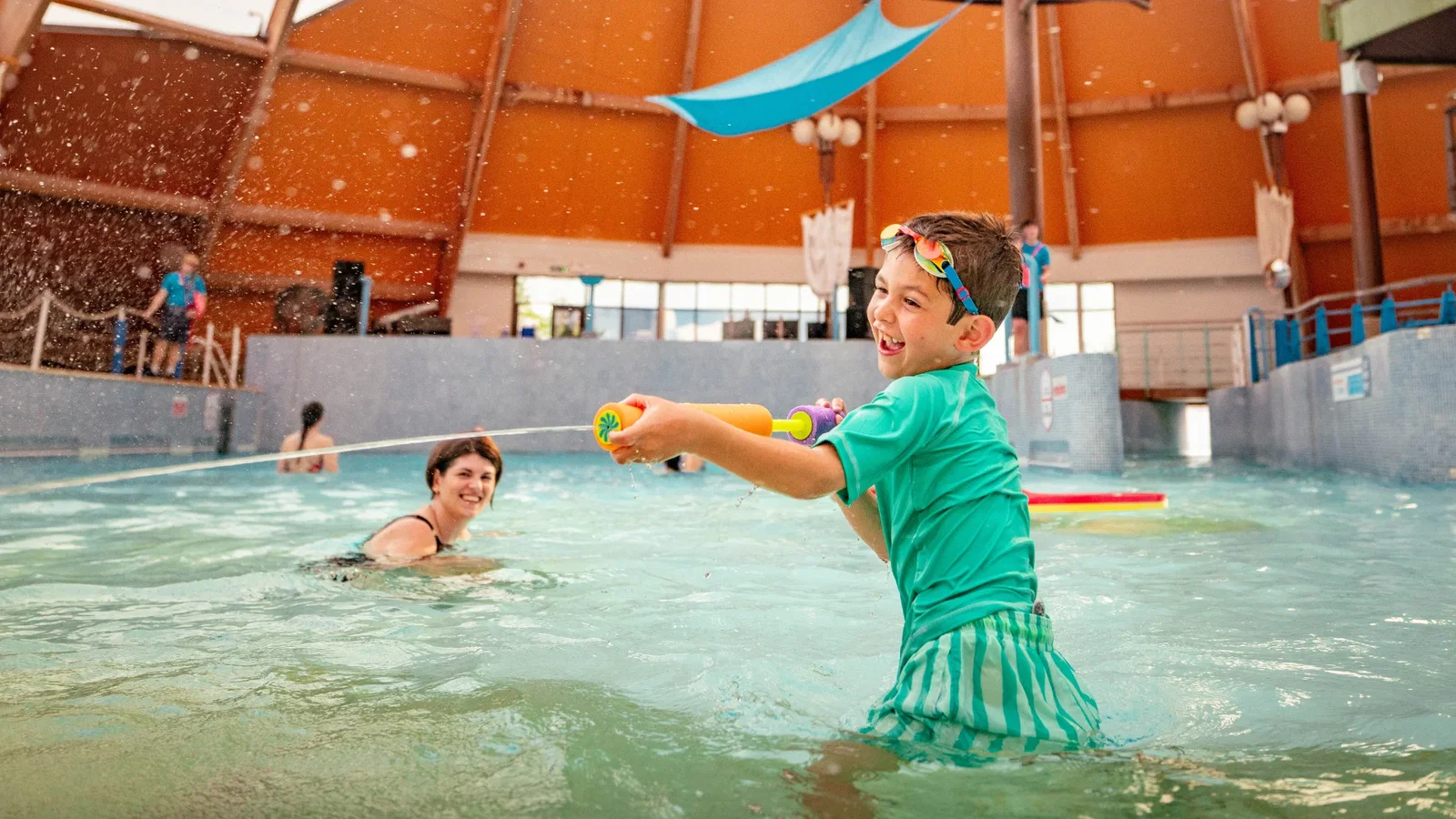 Child playing in the blue lagoon with a water squirter