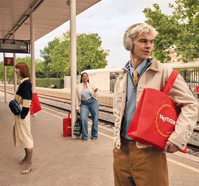 GIF showing three people stood at a train platform, all carrying a TK Maxx tote bag.