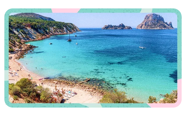 Turquoise and pink border shapes, curved sandy beach, beachgoers, umbrellas, rocky vegetated cliffs, reddish-brown faces, turquoise to deep blue ocean gradient, two rocky islands, pyramidal Es Vedrà formation, green shrubs, clear blue sky and light clouds.