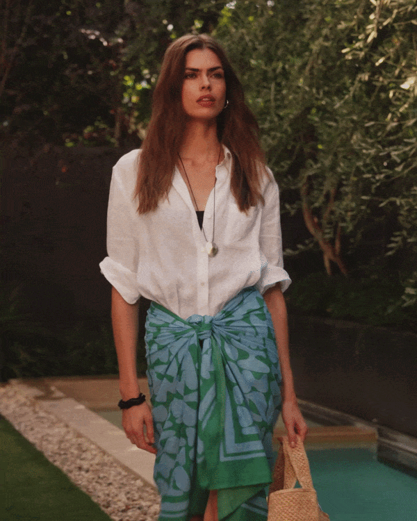 A woman walks into a pool wearing the Roby Sarong.