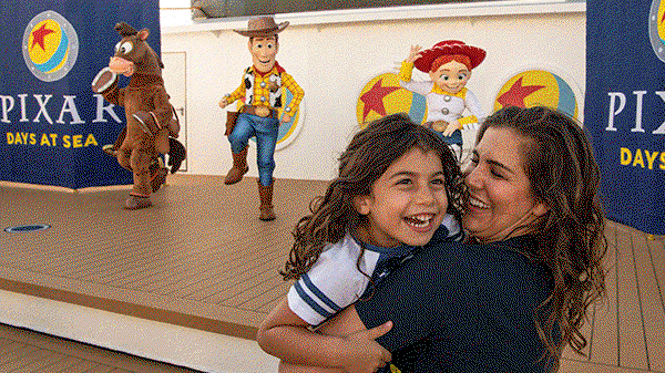 A family takes a selfie in front of a Pixar Day at Sea background, featuring Woody, Frozone and a huge Pixar ball framed by port holes. 