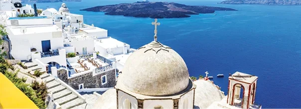 Whitewashed buildings and a domed church overlooking the deep blue sea in Santorini,