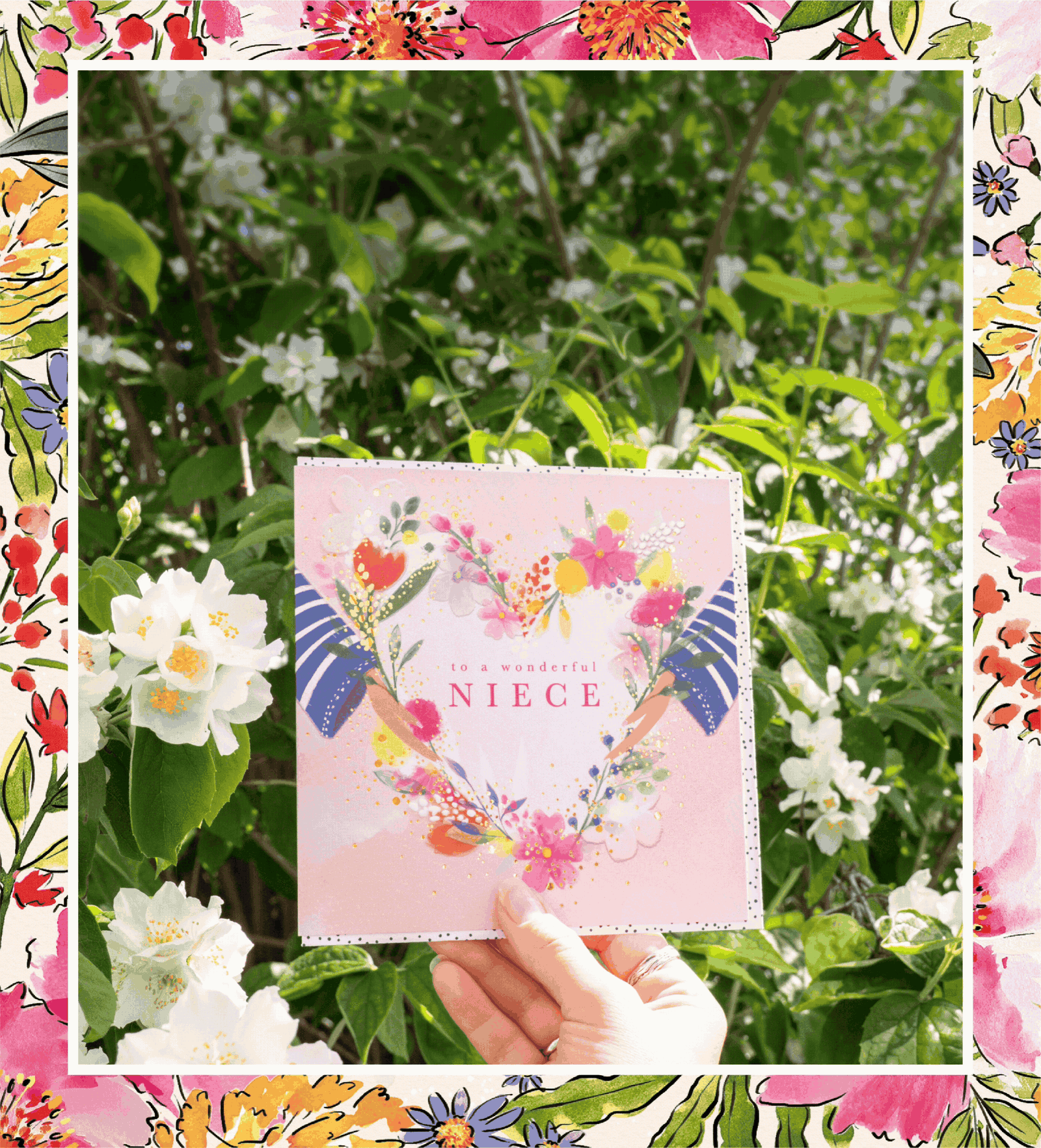 A floral niece greeting card held amongst blooming white jasmine flowers in a summer garden, showcasing Whistlefish's colourful hand painted artwork and premium card finishes.