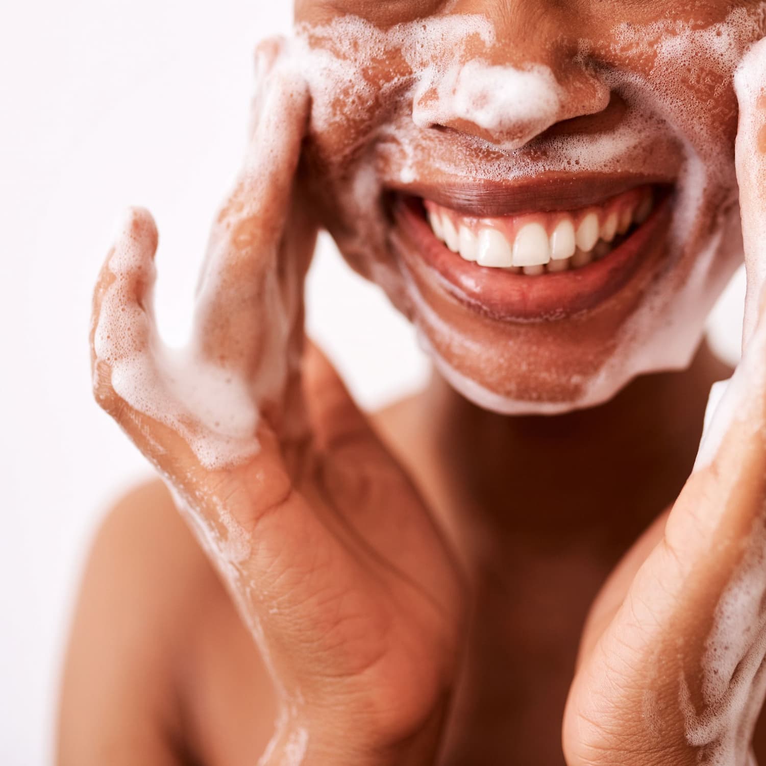 Medium toned woman rubbing cleansing suds into her cheeks