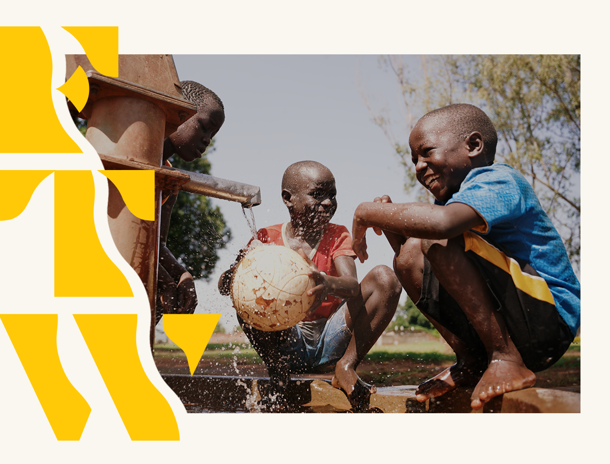 Three boys crouching in front of a tap stand holding a ball