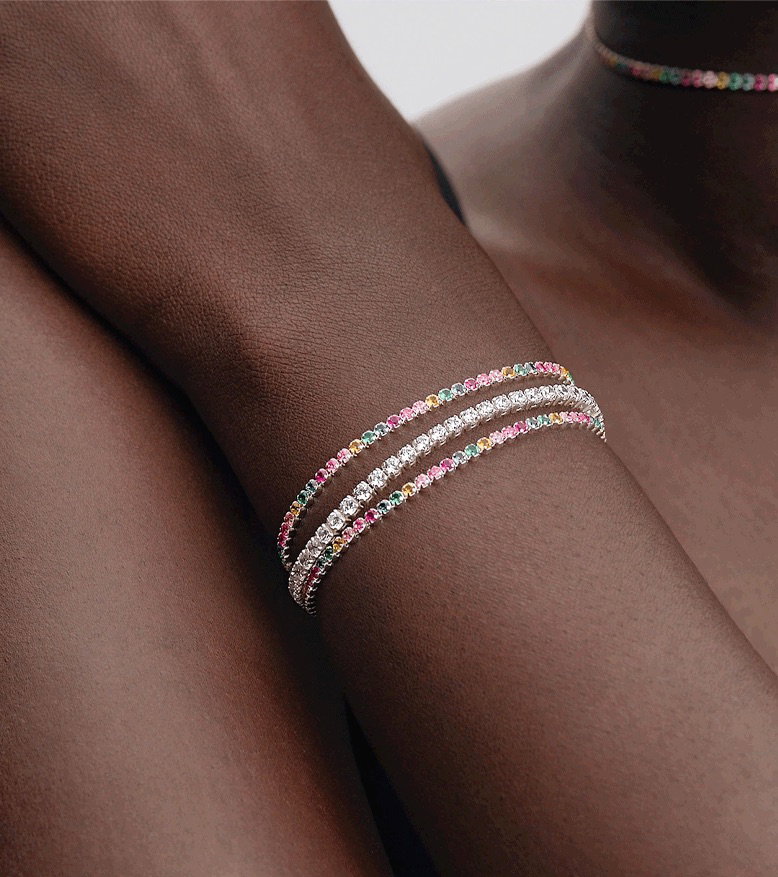  A close up shot of a model's wrist wearing multicoloured Pandora Timeless tennis bracelets.