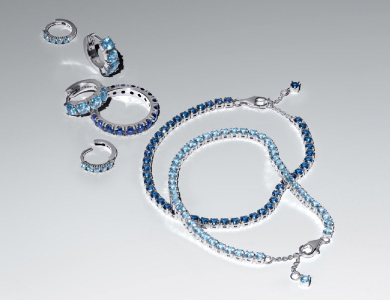 A selection of blue and sterling silver Pandora Timeless jewellery on a grey background.
