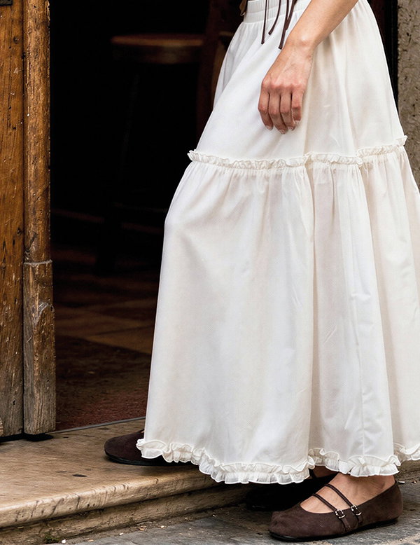 Frauenmodel trägt langen Rock, Weiß, Volants, Rüschen, Kombination mit braunen Schuhen, Vorderansicht