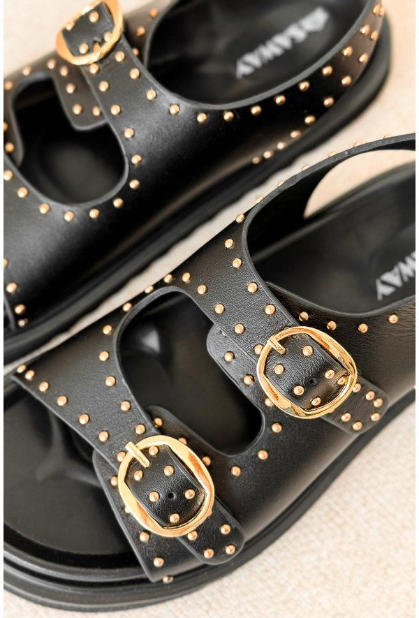 Black leather double-strap sandals with gold stud detailing and round gold buckles, close-up on pair