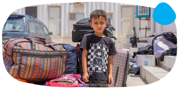 A young boy standing in front of luggage. 