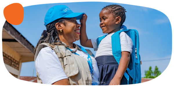 A UNICEF worker carries a smiling child. 