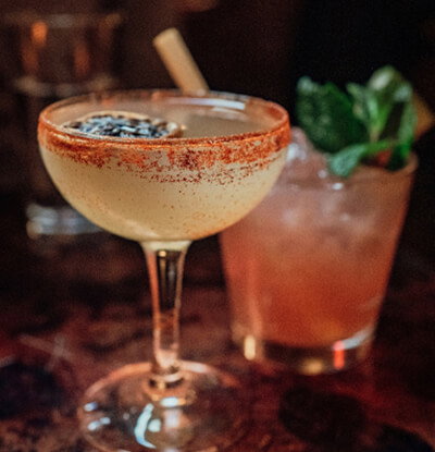 Two cocktail glasses on a dark background