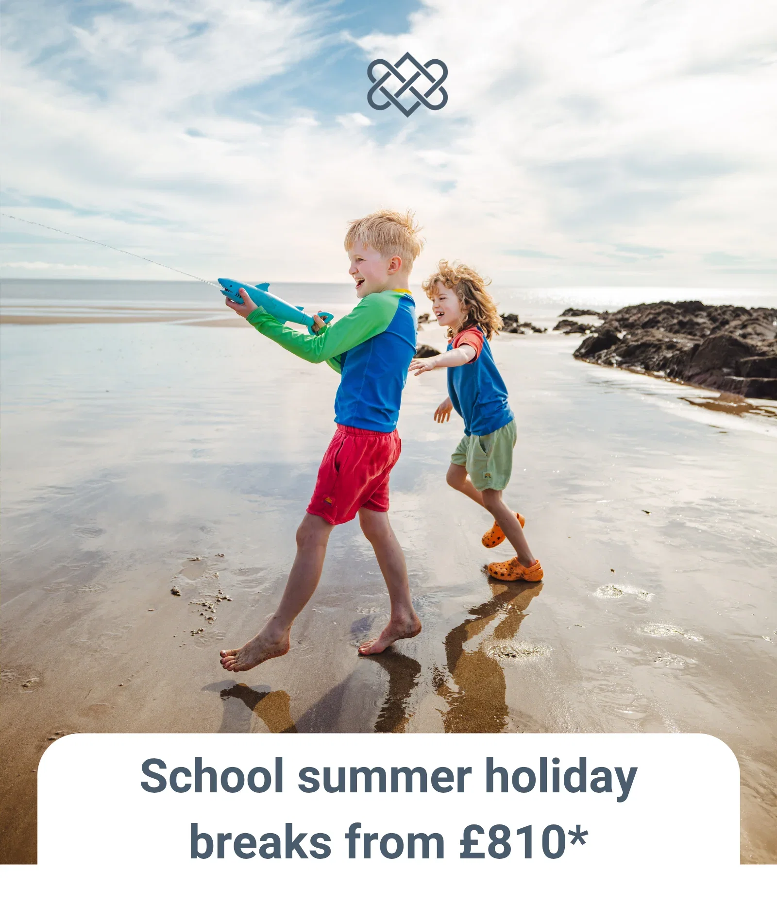 Two children having fun playing with water pistols on the beach