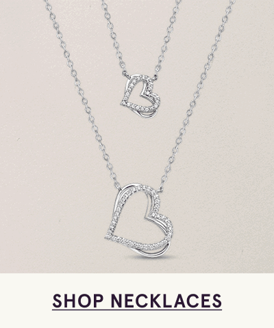 Silver layered necklace set with two open heart-shaped diamond pendants. Click here to shop necklaces