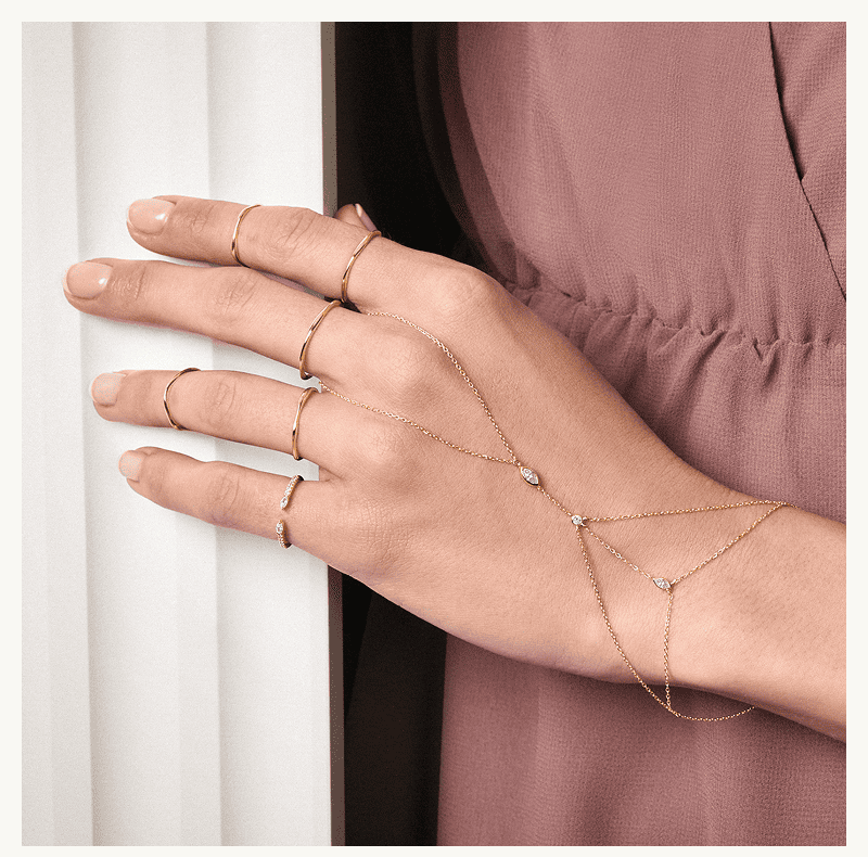 A model wearing a hand chain bracelet and several rings. 