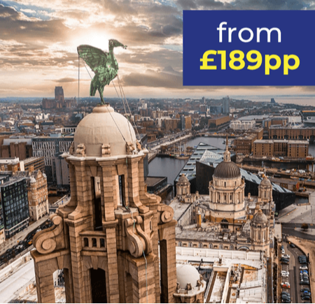 Aerial view of a city skyline featuring historic buildings and a prominent statue on a dome.