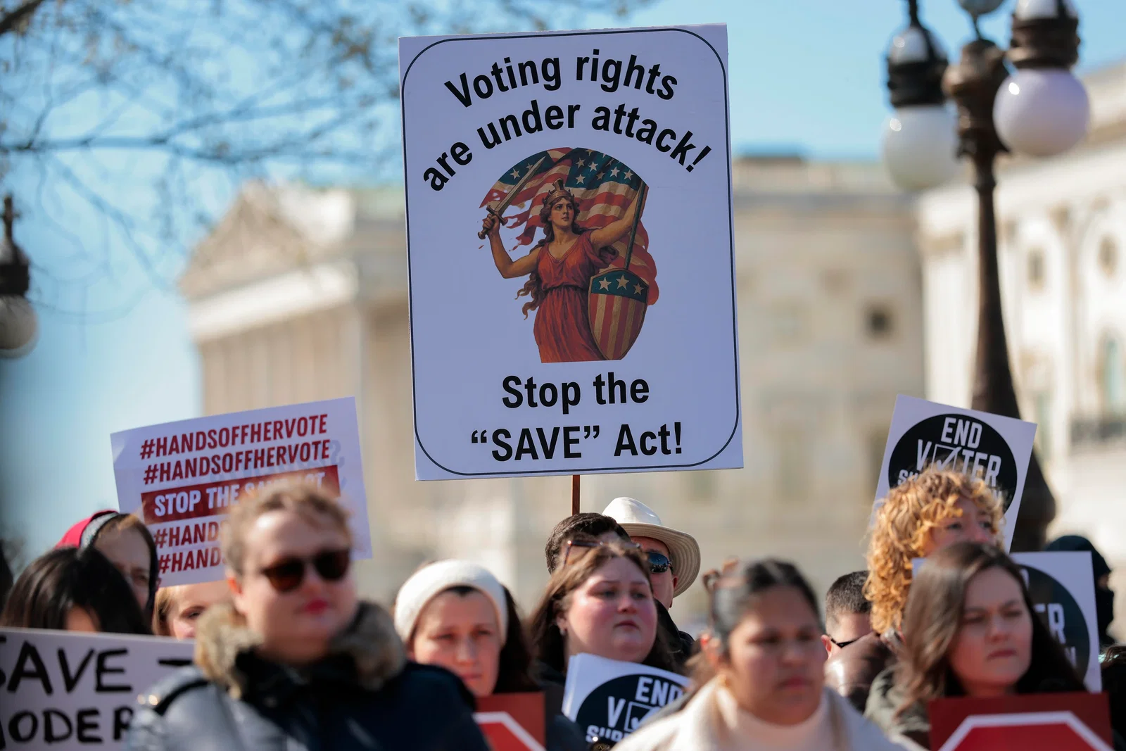 Protesters holding signs against the SAVE Act.