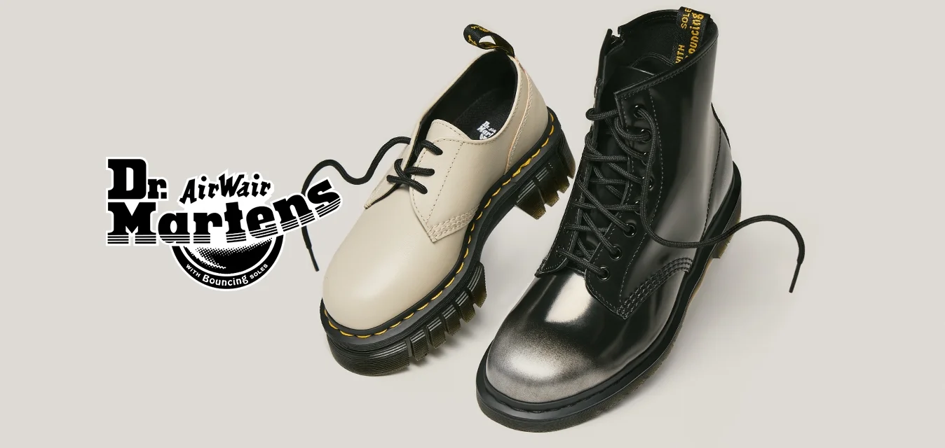Ein beiger, tief ausgeschnittener Schuh und ein schwarzer, hoch geschnittener Stiefel mit Schnürsenkeln vor einem schlichten, hellen Hintergrund.
