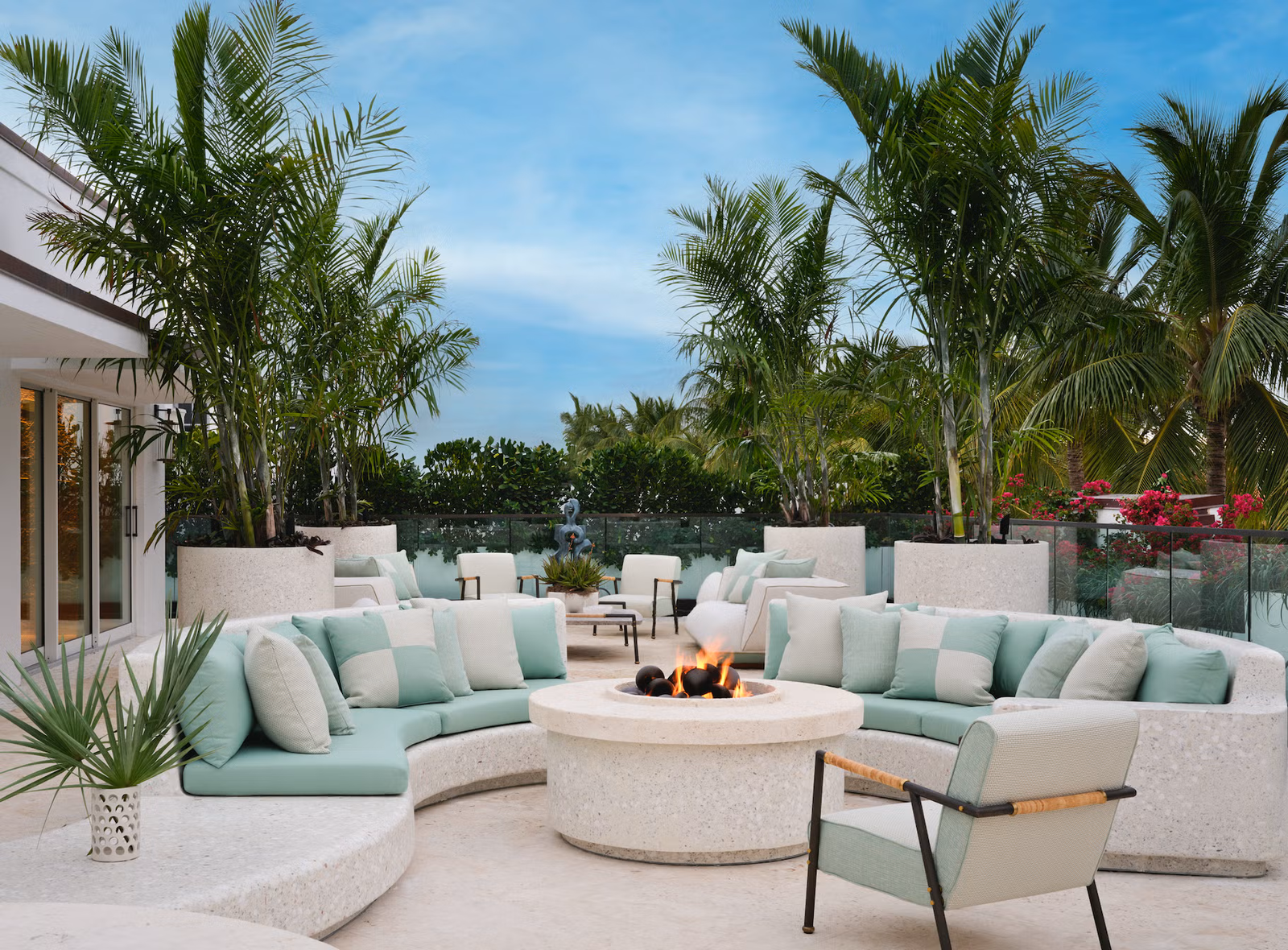 outdoor seating area with a firepit surrounded by palm trees