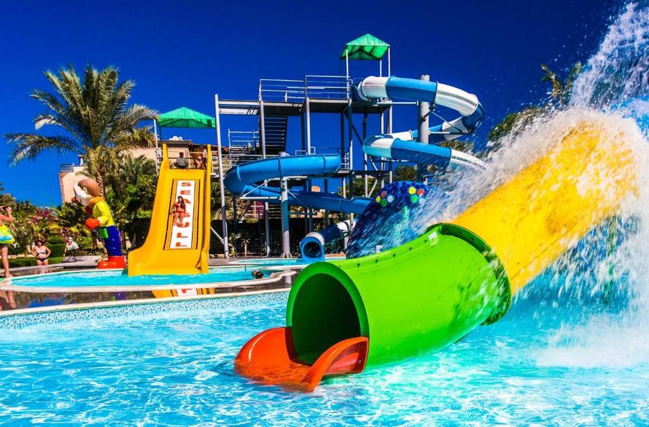 Colourful water slides and splash pool at a sunny family waterpark with twisting chutes and people enjoying rides