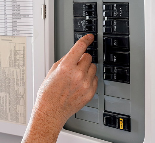 A close up shot of a hand turning off a breaker
