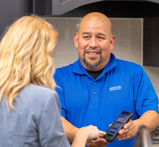 A Sears Home Services technician shows a customer their invoice