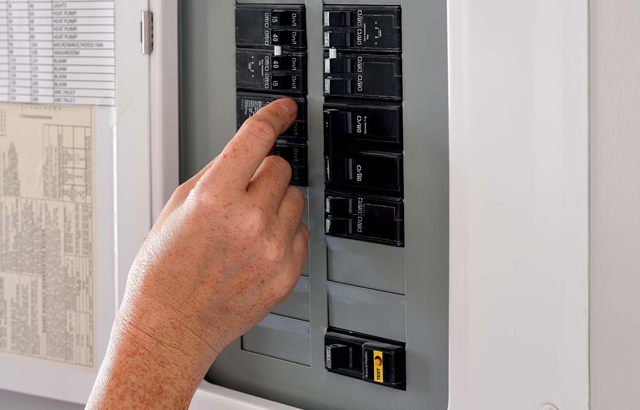A close up shot of a hand turning off a breaker
