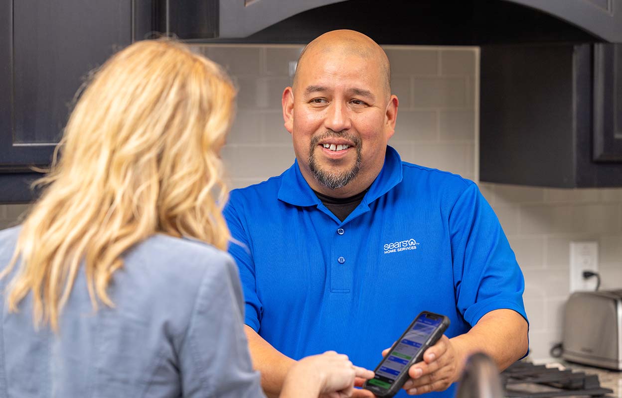 A Sears Home Services technician shows a customer their invoice