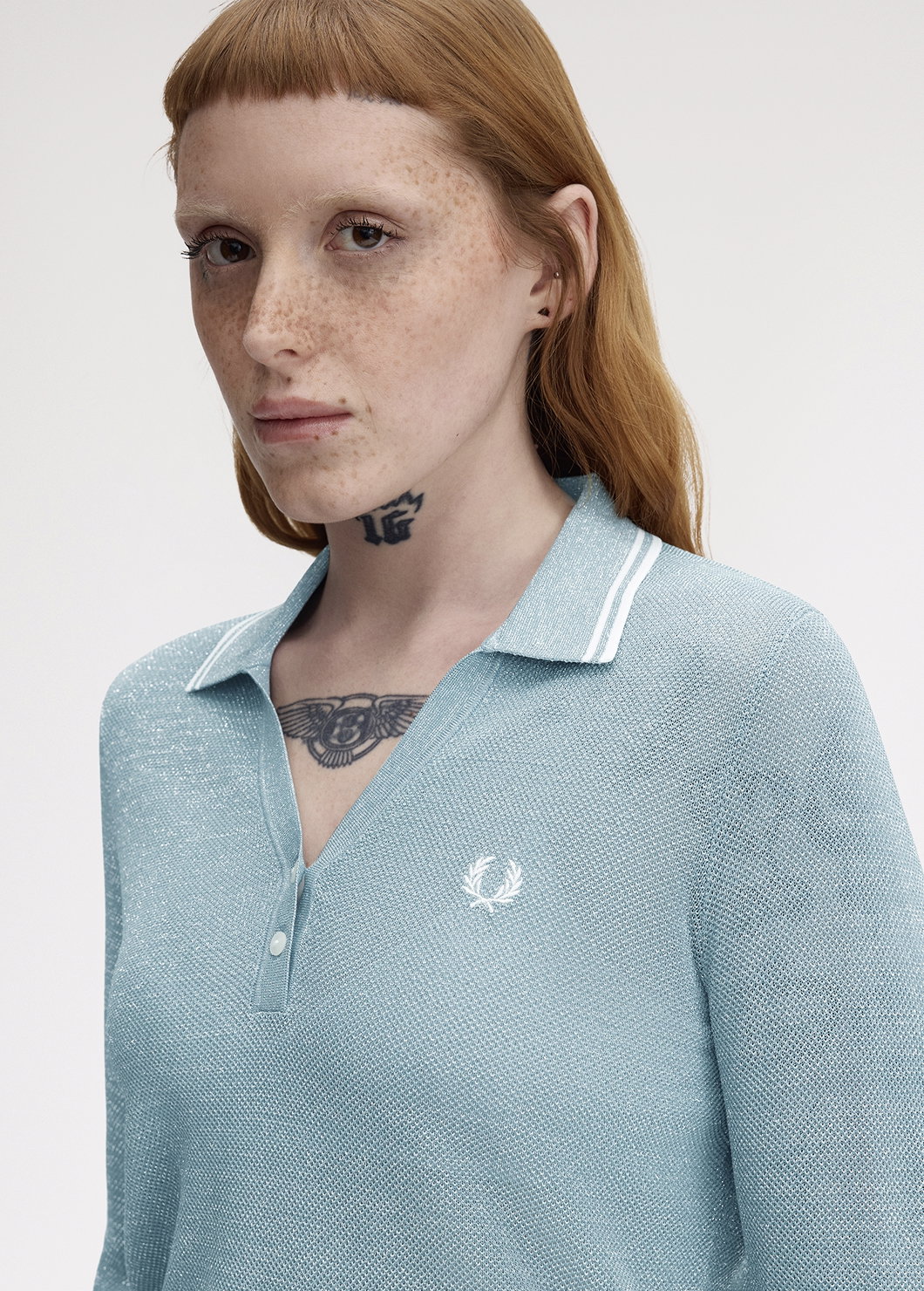 Female model wearing a Fred Perry Textured Metallic Knit Polo Shirt in Stockport Blue