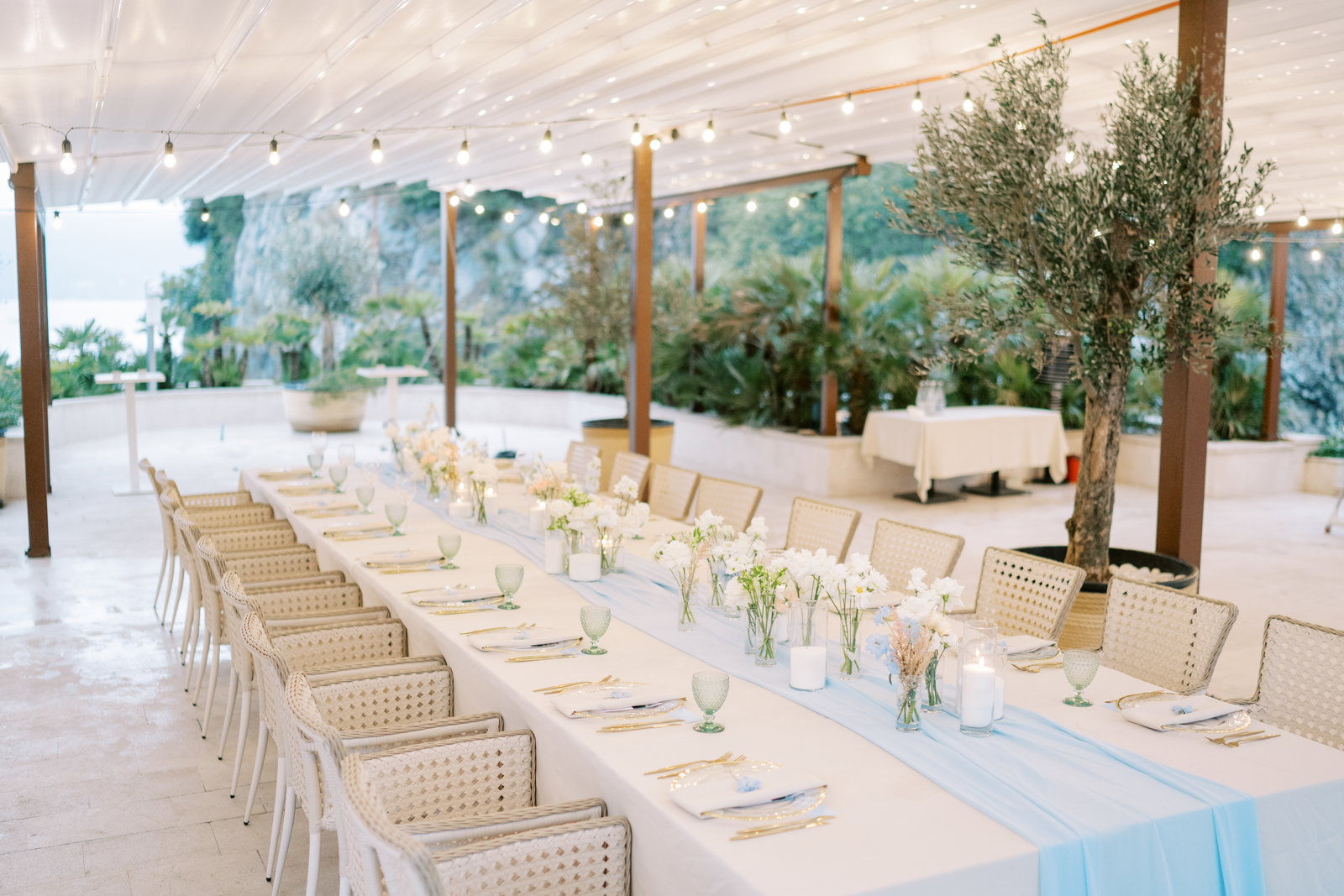 Elegant outdoor wedding reception with white linens, peach florals and string lights