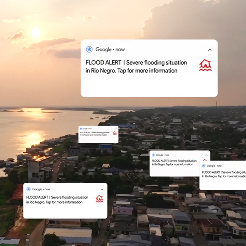 Aerial sunset view of a coastal town with Google flood alert notifications for Rio Negro.