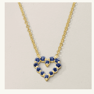 A gold necklace with a heart shaped, blue gemstone pendant.