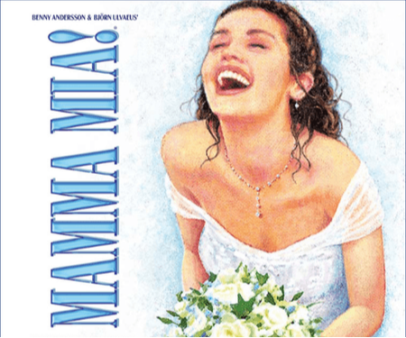 A joyful woman in a wedding dress laughing while holding a bouquet of flowers.