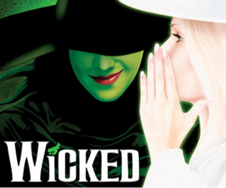 A dark figure in a green face mask whispers to a blonde woman, with the title "Wicked" prominently displayed.