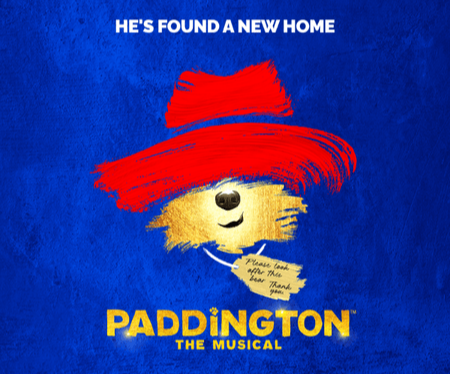 Paddington Bear in a red hat with a blue background, promoting "Paddington: The Musical."
