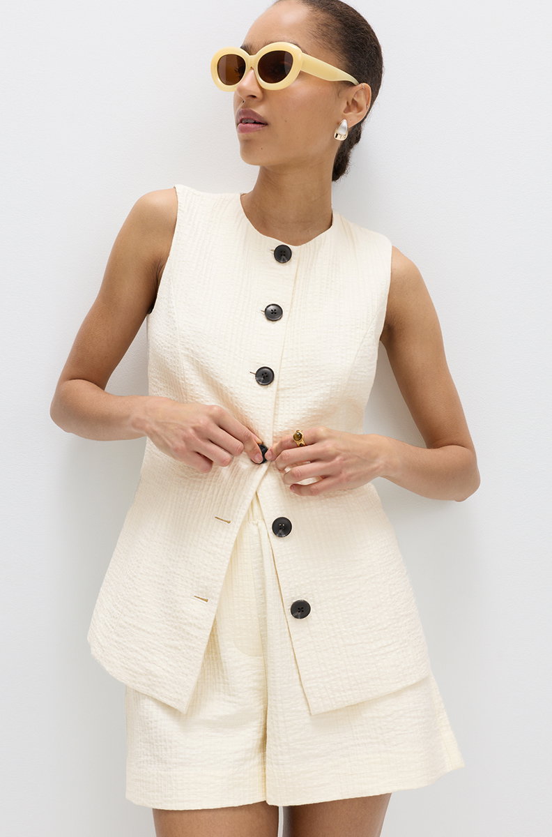 Women wearing an Ivory Cotton Blend Textured Longline Waistcoat and Ivory Cotton Blend High Waisted Shorts 