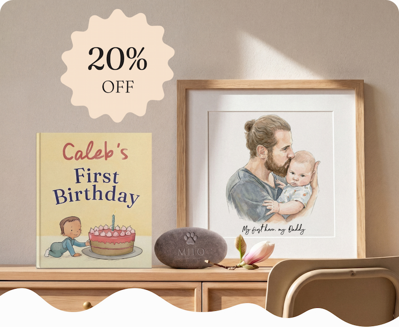 A personalised birthday book and framed watercolour portrait of a father and baby, displayed on a wooden sideboard with dried flowers