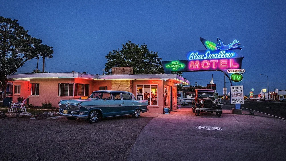 Image description: Vintage cars parked outside Blue Swallow Motel in Tucumcari, New Mexico.

