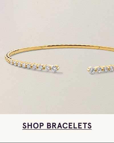 Slender, open-style golden cuff bracelet with embedded stones. Click here to shop bracelets