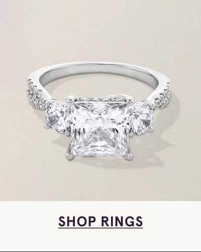 White metal ring with central square-stone flanked by stones on band. Click here to shop rings