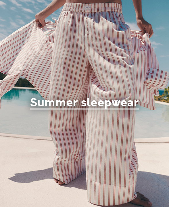 Model wearing Pure Cotton Striped Wide Leg Pyjama Bottoms in Red Mix by a pool
