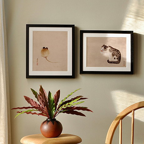 Two Japanese animal-themed prints, one featuring a mouse and the other a cat, framed in black and hung on a light wall – Custom Prints.