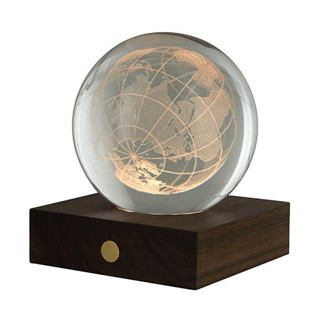 Amber crystal globe light with a three-dimensional Earth design on a wooden stand. - Shop Now.