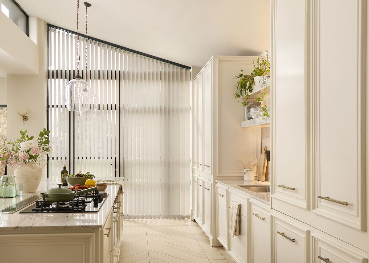 Floor-to-ceiling white vertical blinds tailored to a large, angled sloping kitchen window