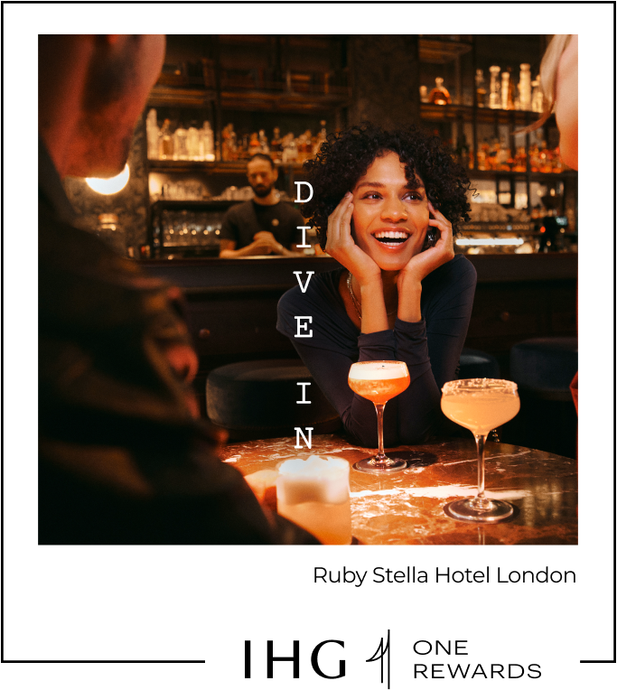 A woman smiles while seated at a dimly lit bar at Ruby Stella Hotel London.
