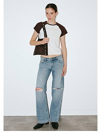 Woman wearing cream and black t-shirt with distressed jeans
