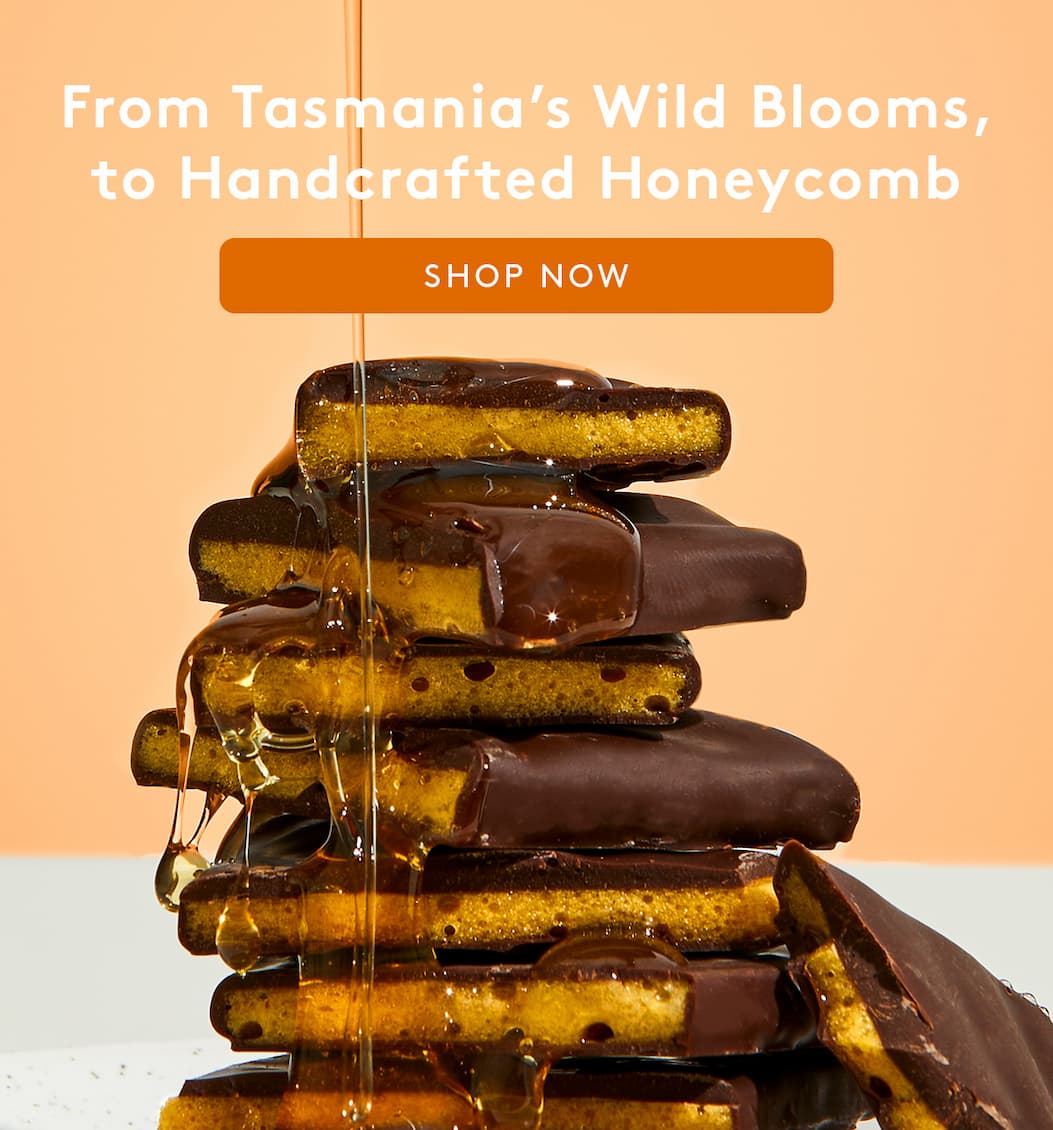 Honey being drizzled over pieces of stacked honeycomb 